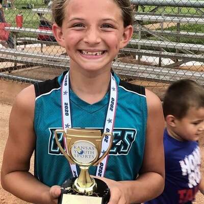 Young softball player with her Kansas Youth Sports trophy